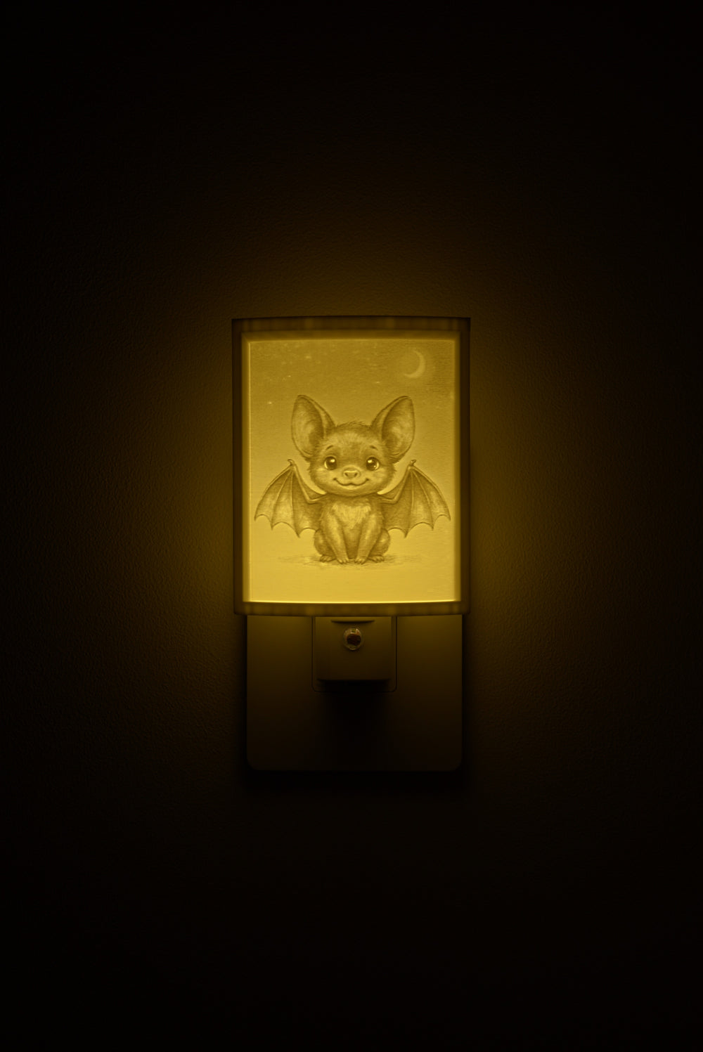 Bat night light glowing against a dark wall, plugged into an outlet