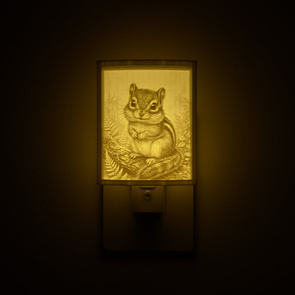 Chipmunk night light glowing against a dark wall, plugged into an outlet