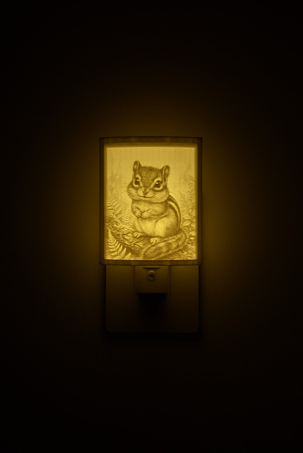 Chipmunk night light glowing against a dark wall, plugged into an outlet