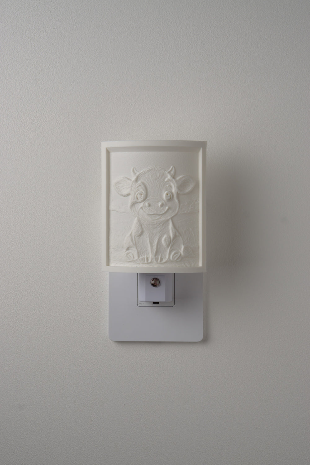 Cow night light switched off — a soft ivory panel by day