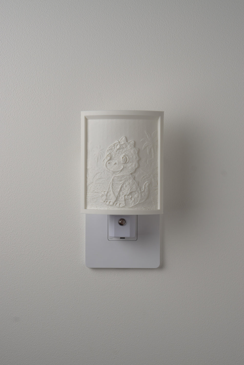 Dinosaur night light switched off — a soft ivory panel by day