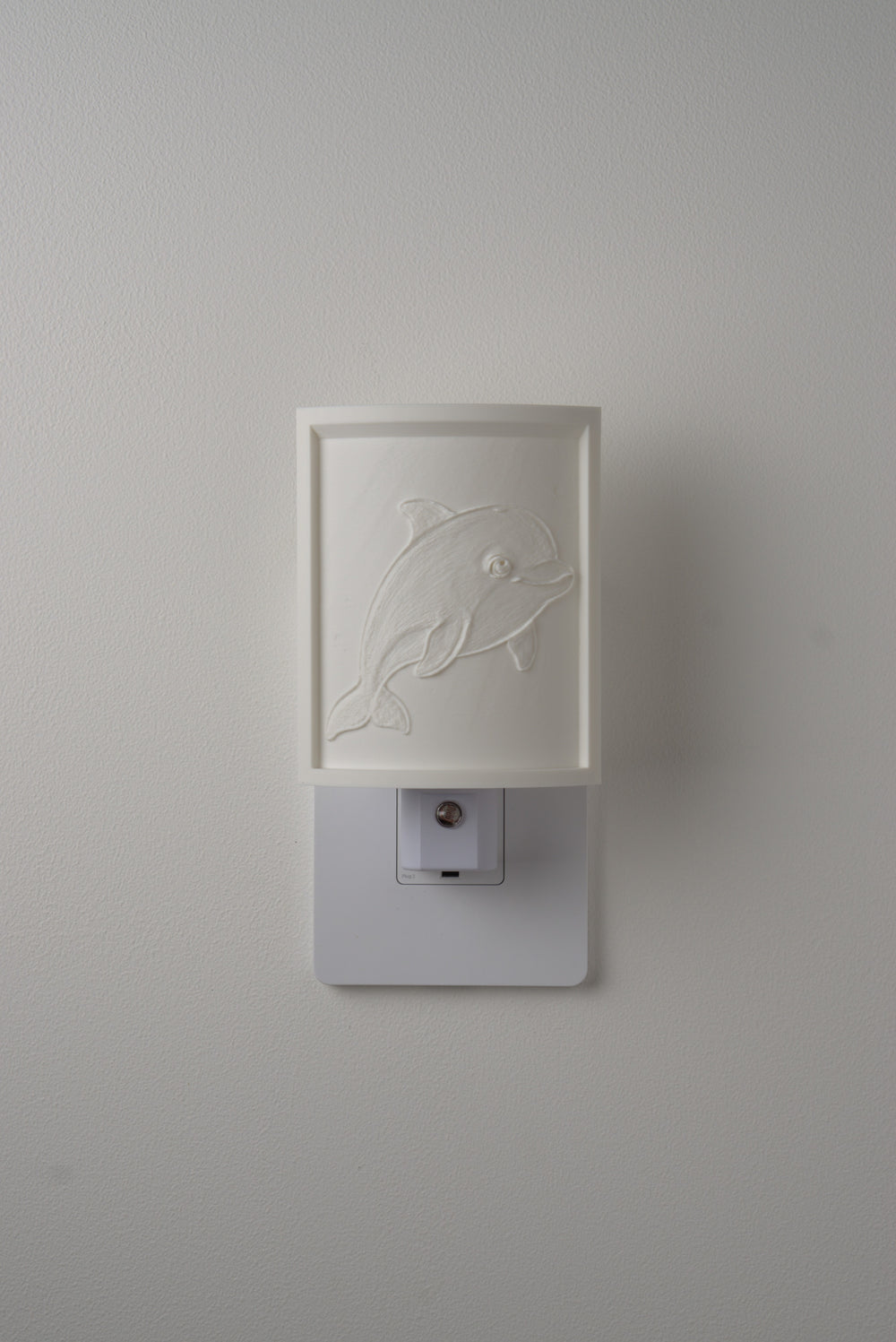 Dolphin night light switched off — a soft ivory panel by day