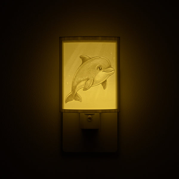 Dolphin night light glowing against a dark wall, plugged into an outlet