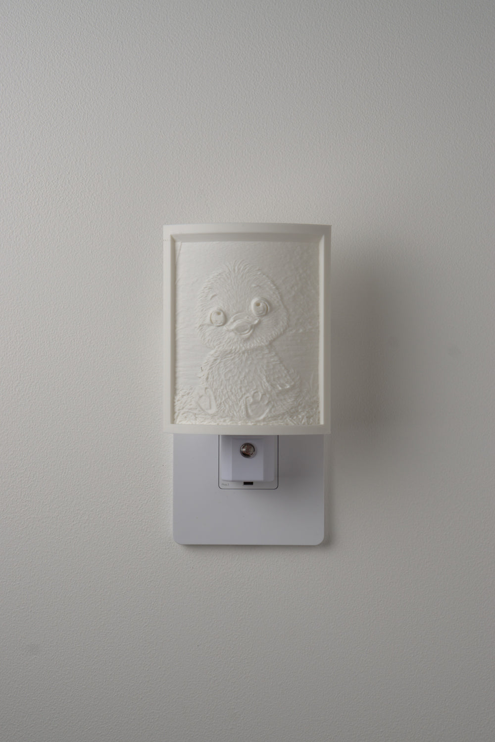 Duckling night light switched off — a soft ivory panel by day