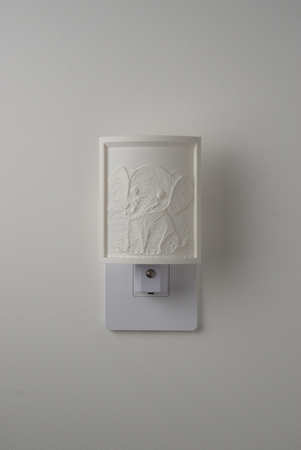 Elephant night light switched off — a soft ivory panel by day