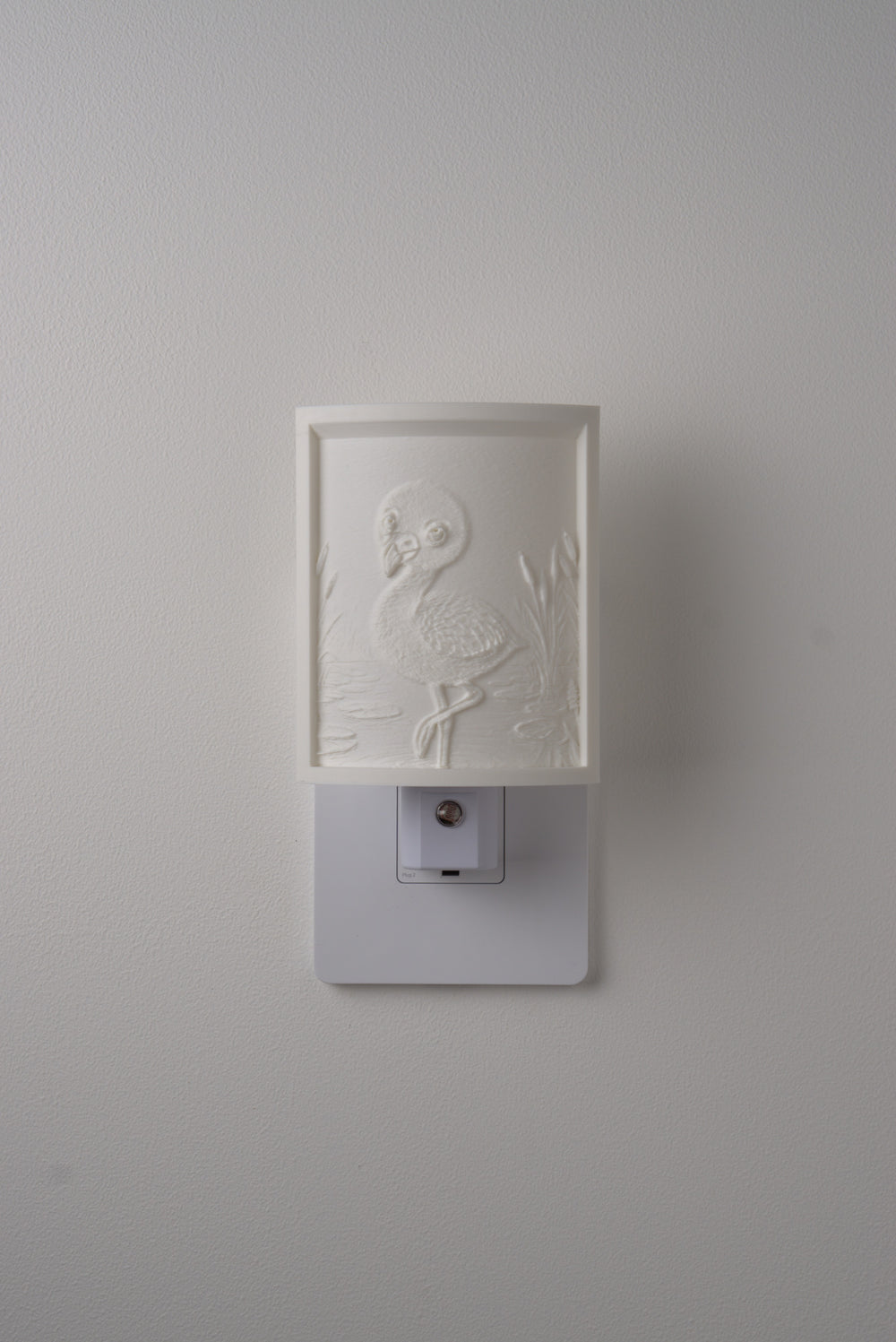 Flamingo night light switched off — a soft ivory panel by day