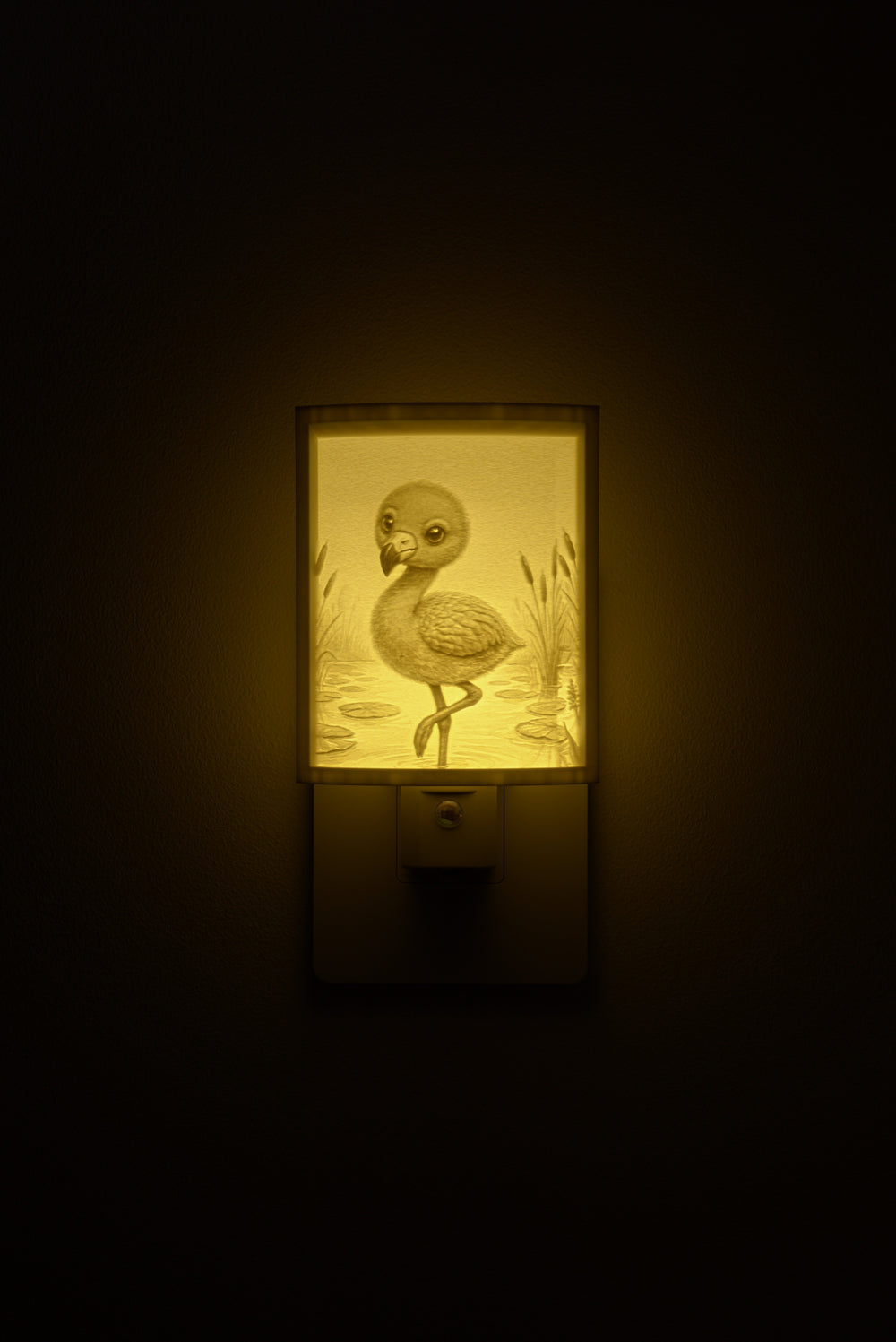 Flamingo night light glowing against a dark wall, plugged into an outlet