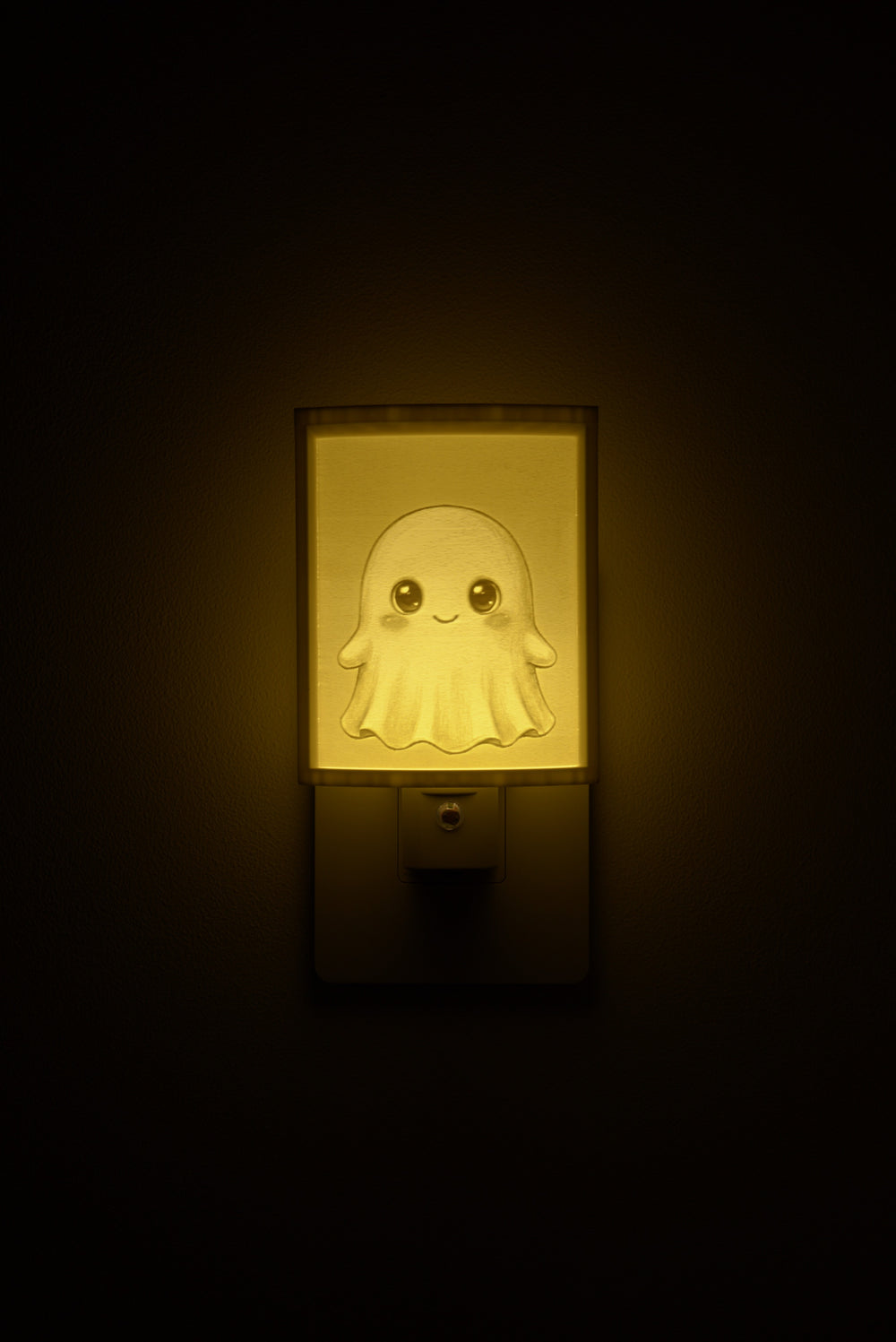 Ghost night light glowing against a dark wall, plugged into an outlet