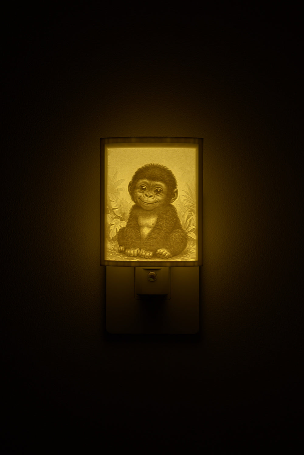 Gorilla night light glowing against a dark wall, plugged into an outlet