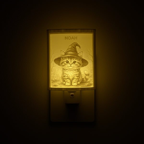 Kitten in a Witch Hat night light glowing with the name NOAH sculpted into the panel