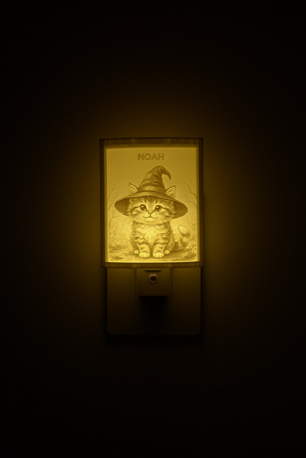Kitten in a Witch Hat night light glowing with the name NOAH sculpted into the panel