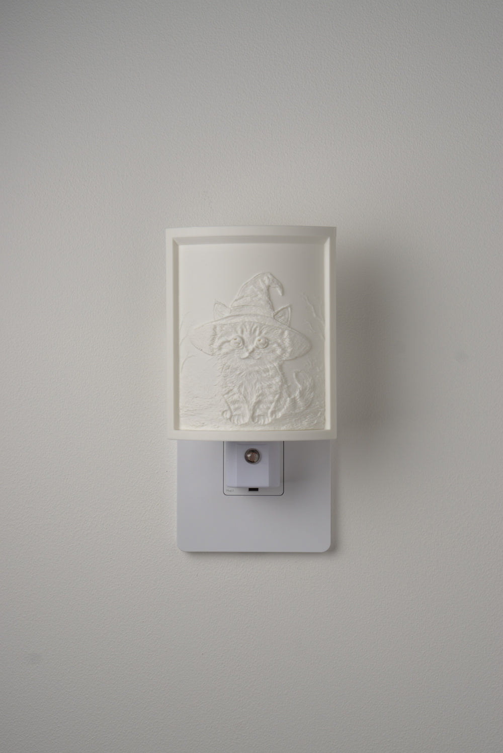 Kitten in a Witch Hat night light switched off — a soft ivory panel by day
