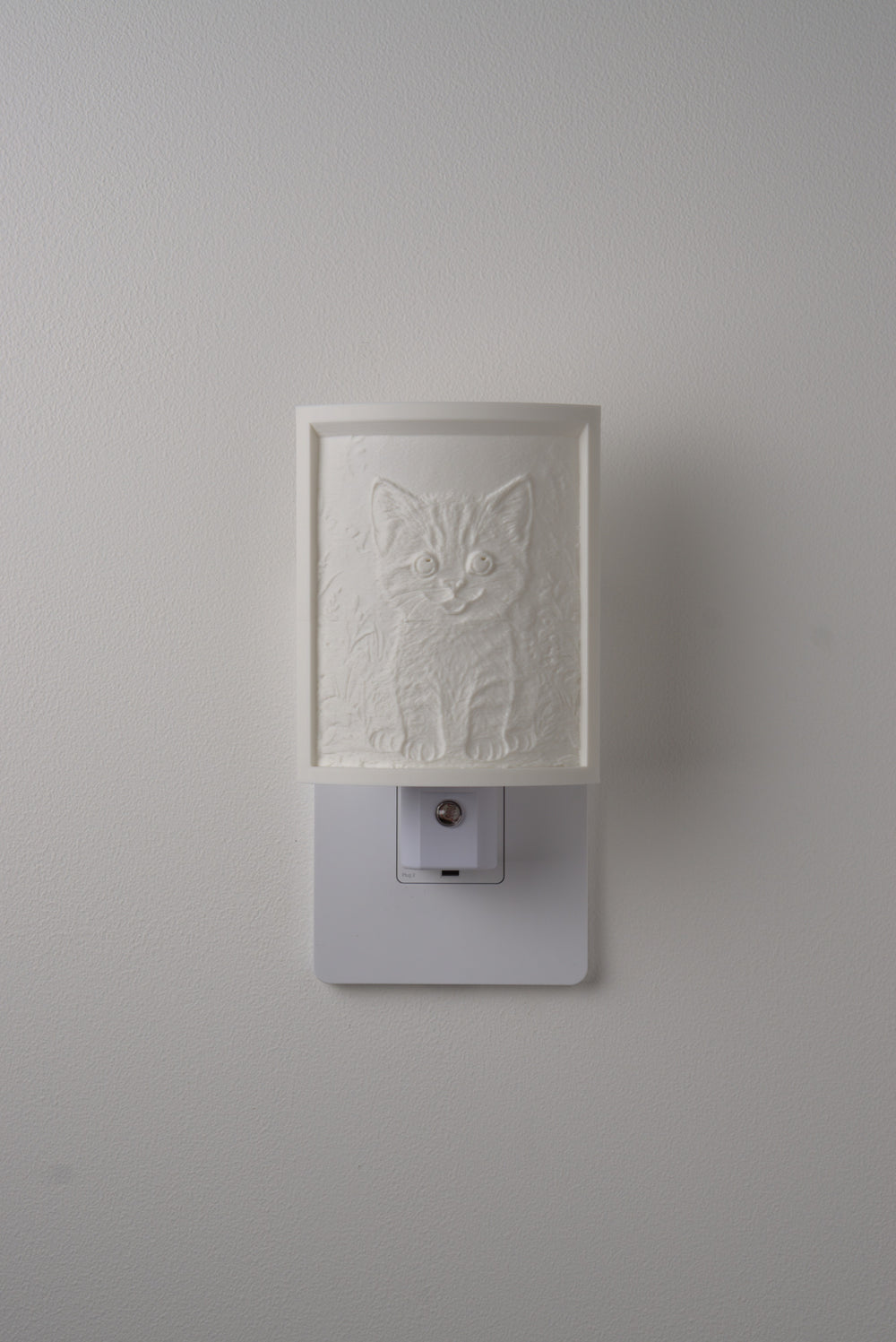 Kitten night light switched off — a soft ivory panel by day
