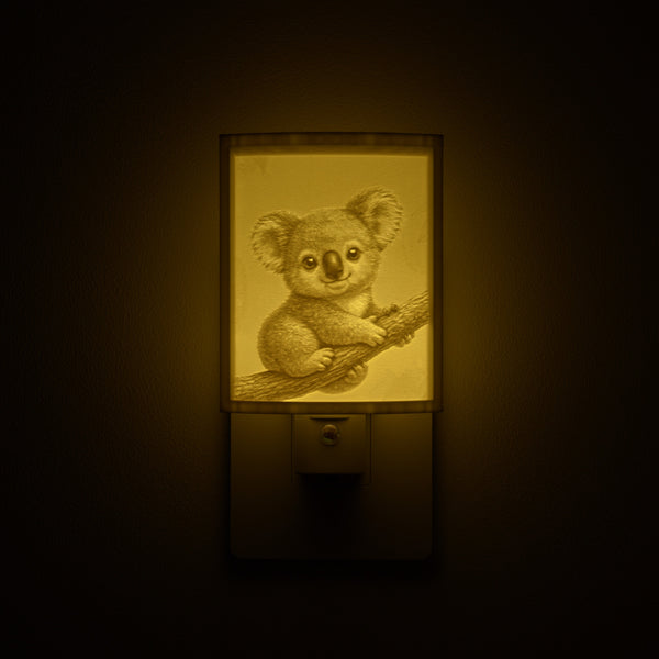 Koala night light glowing against a dark wall, plugged into an outlet