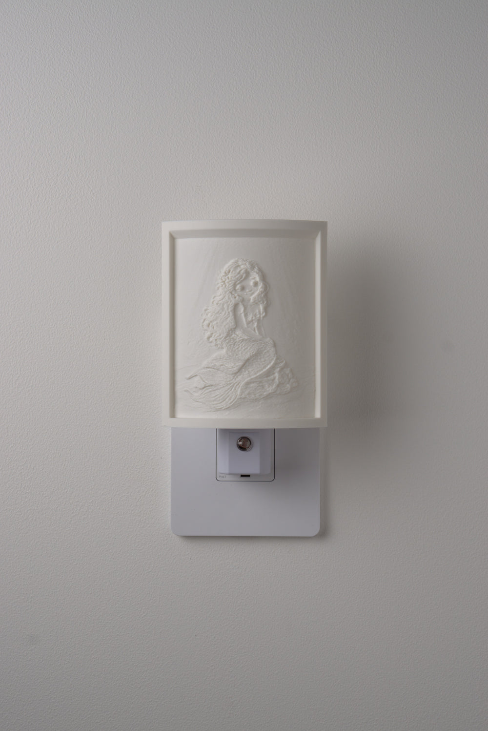 Mermaid night light switched off — a soft ivory panel by day