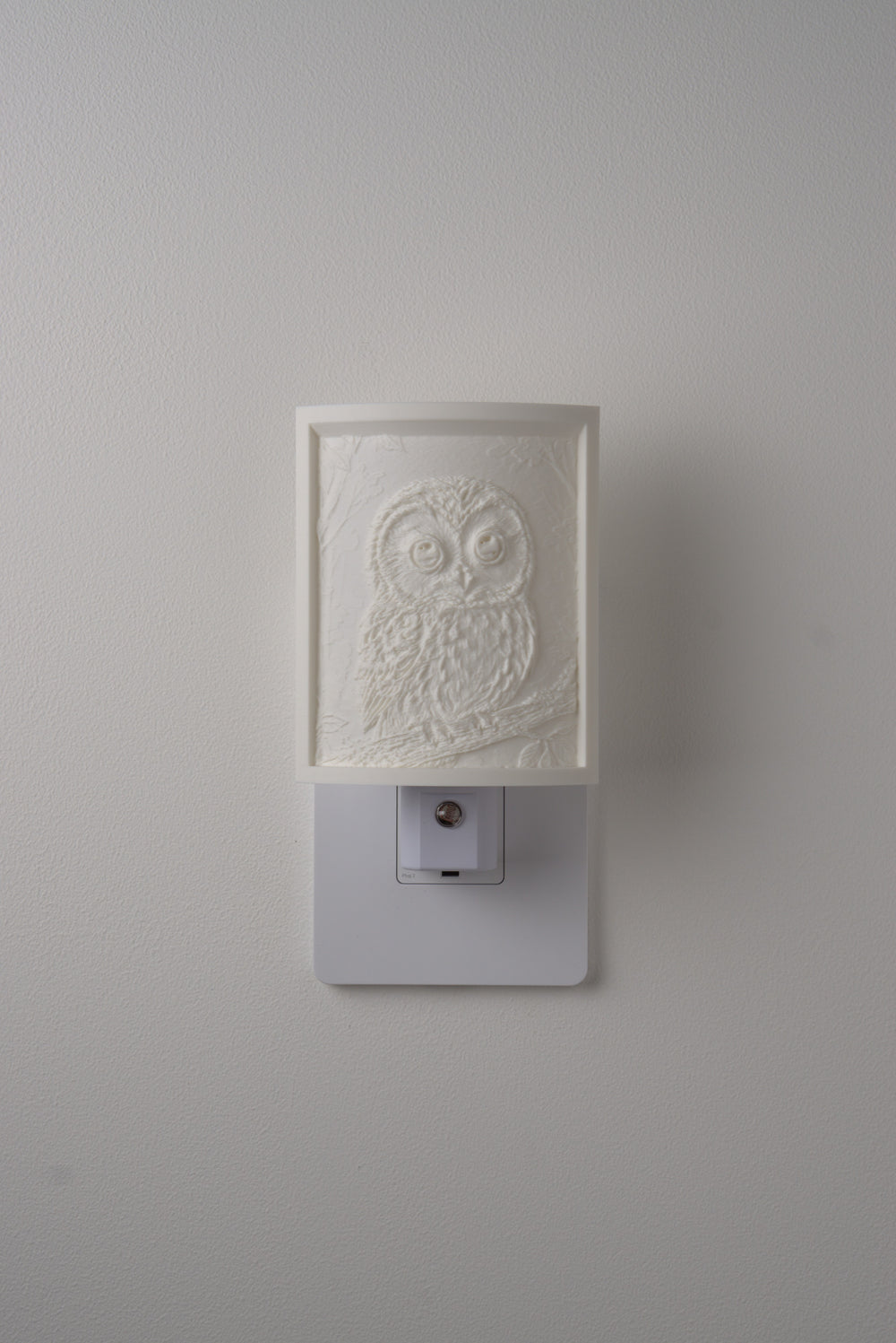 Owl night light switched off — a soft ivory panel by day