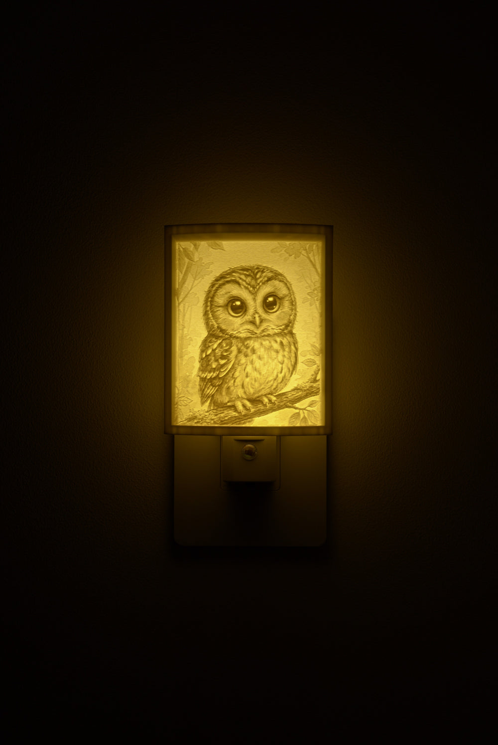 Owl night light glowing against a dark wall, plugged into an outlet