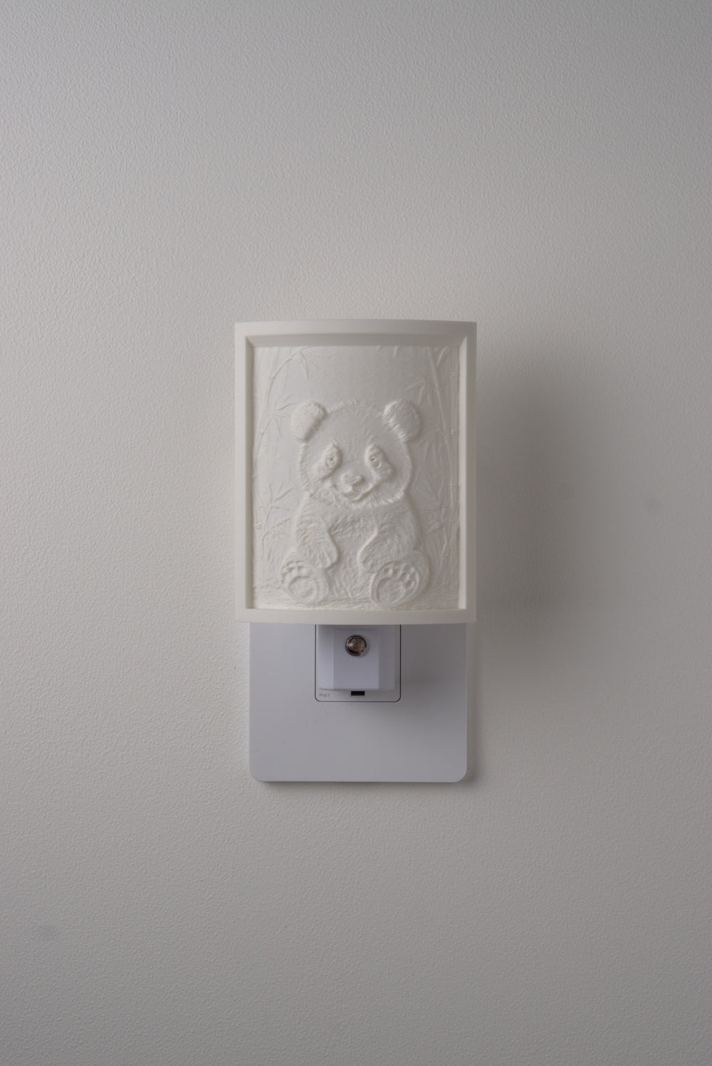 Panda night light switched off — a soft ivory panel by day
