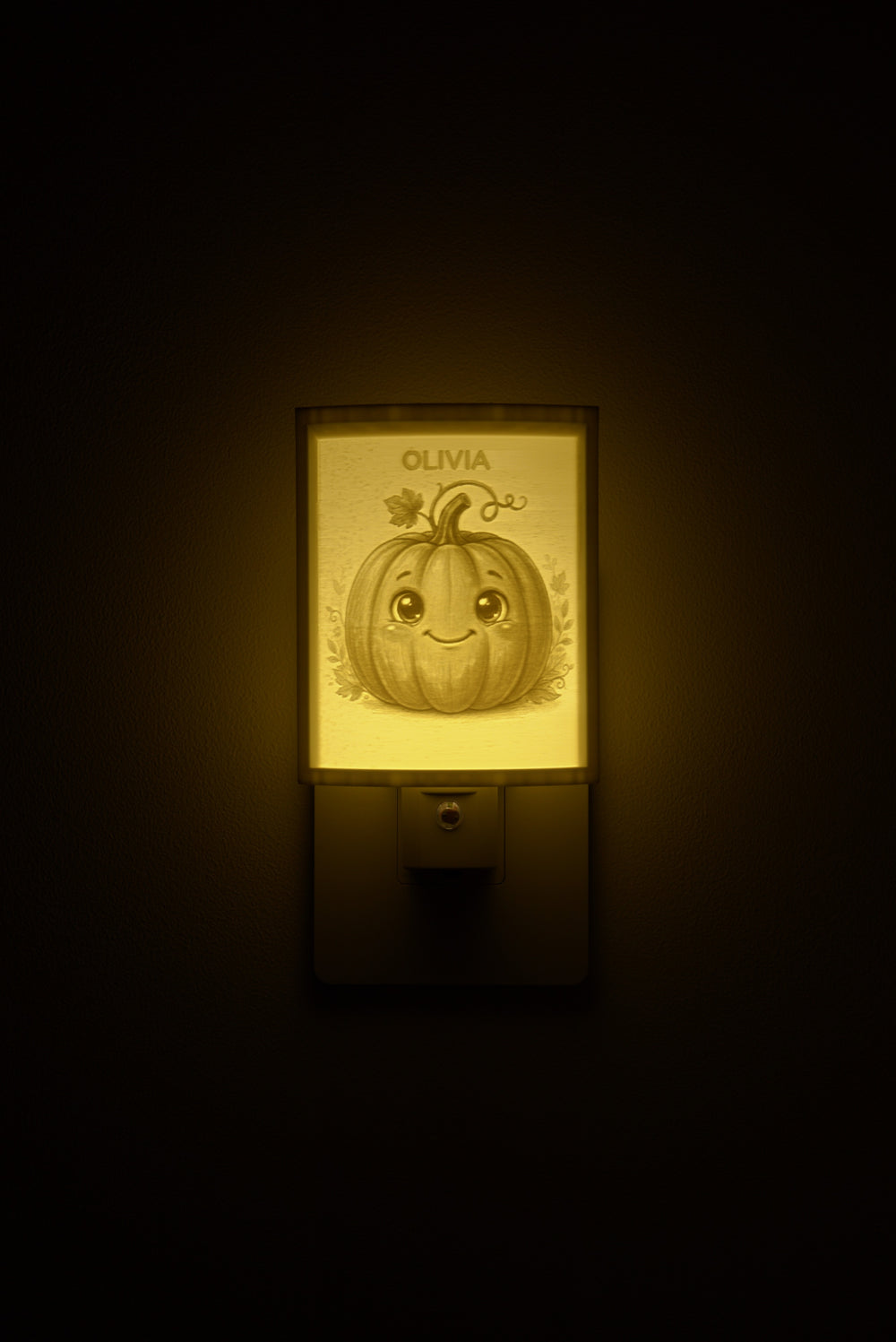 Pumpkin night light glowing with the name OLIVIA sculpted into the panel