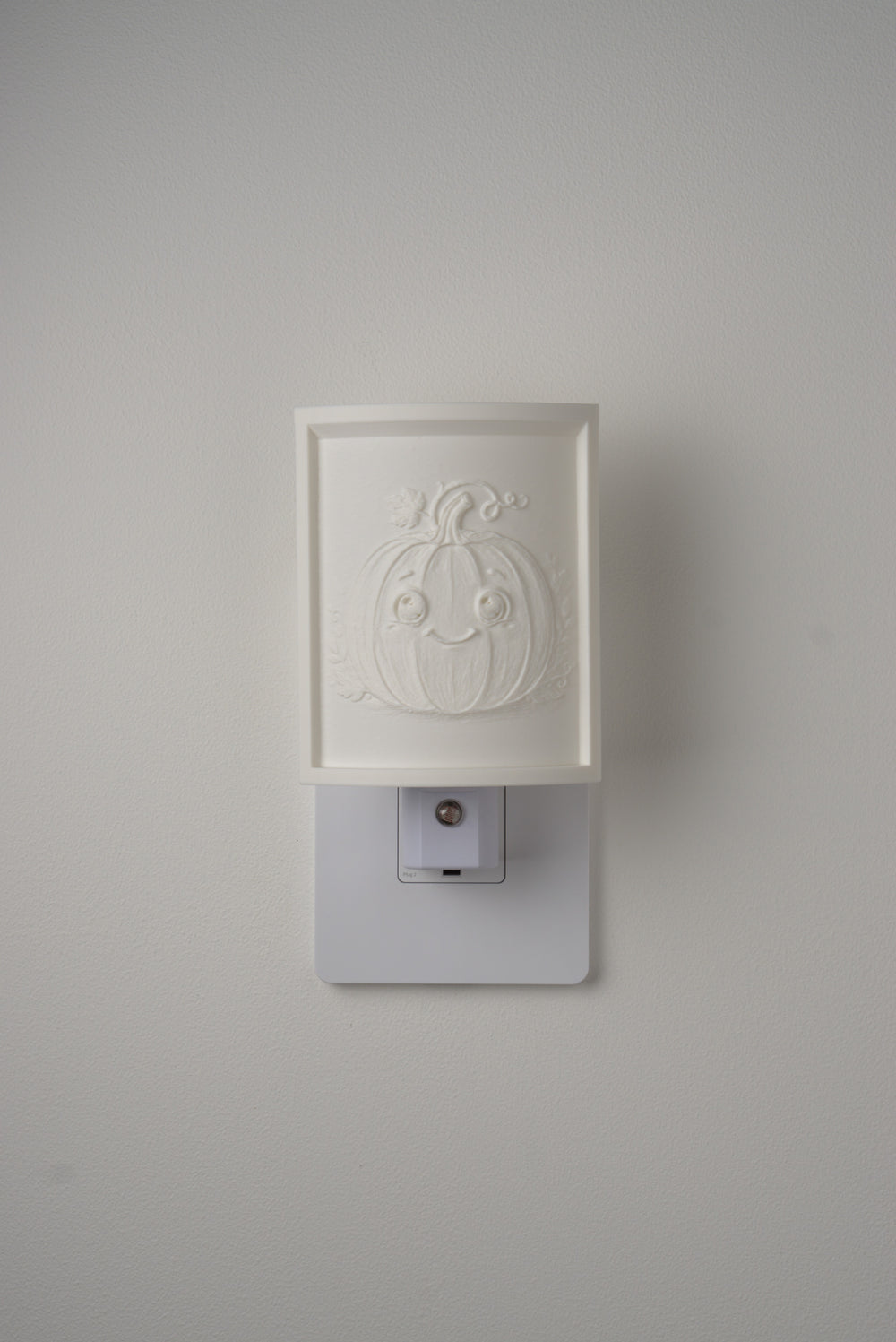 Pumpkin night light switched off — a soft ivory panel by day
