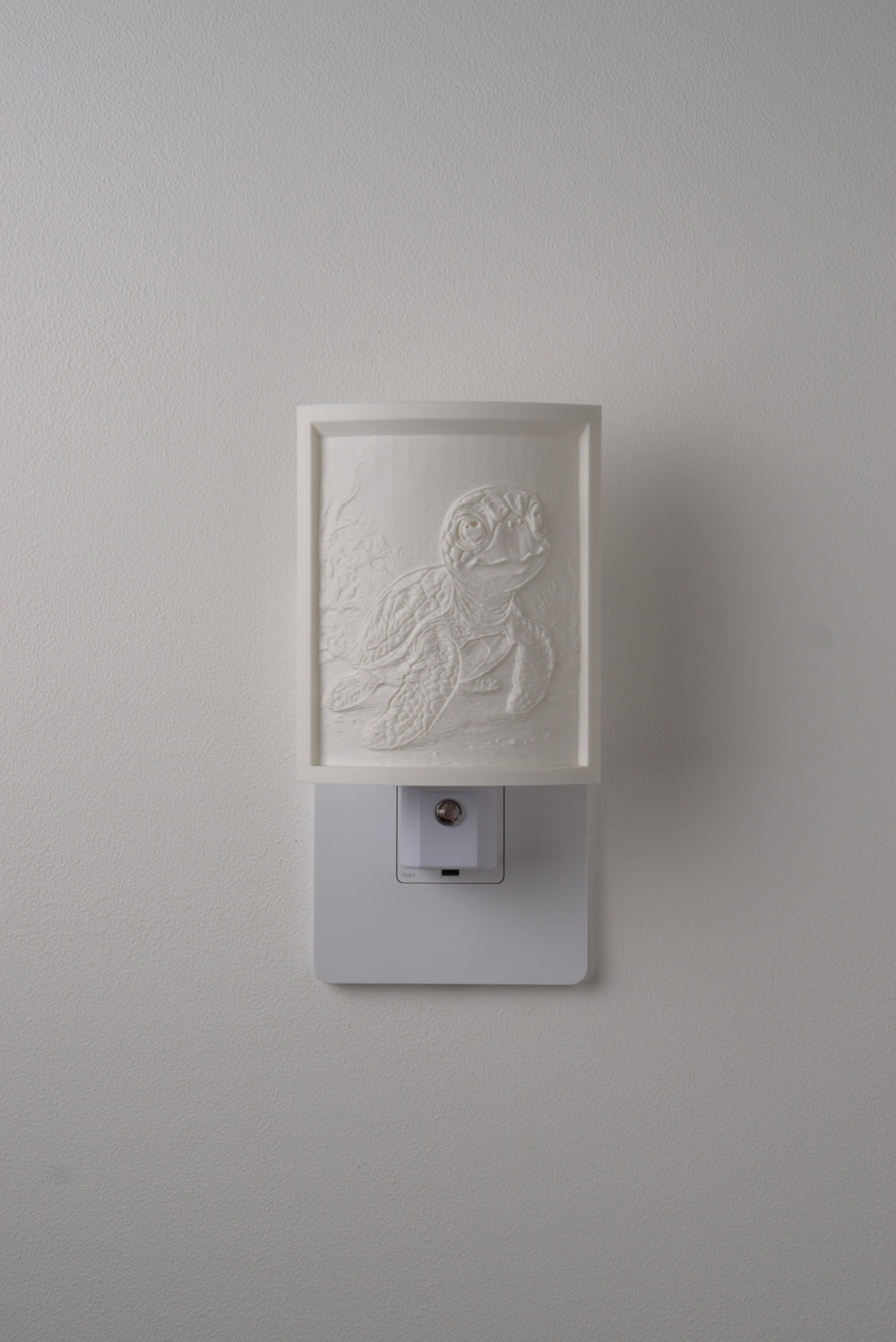 Sea Turtle night light switched off — a soft ivory panel by day