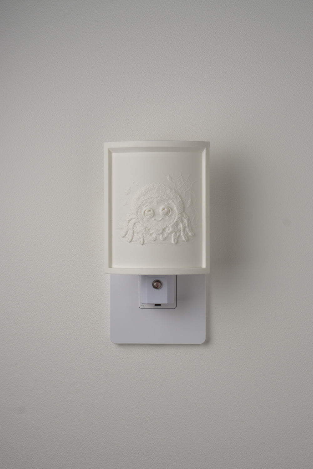 Spider night light switched off — a soft ivory panel by day