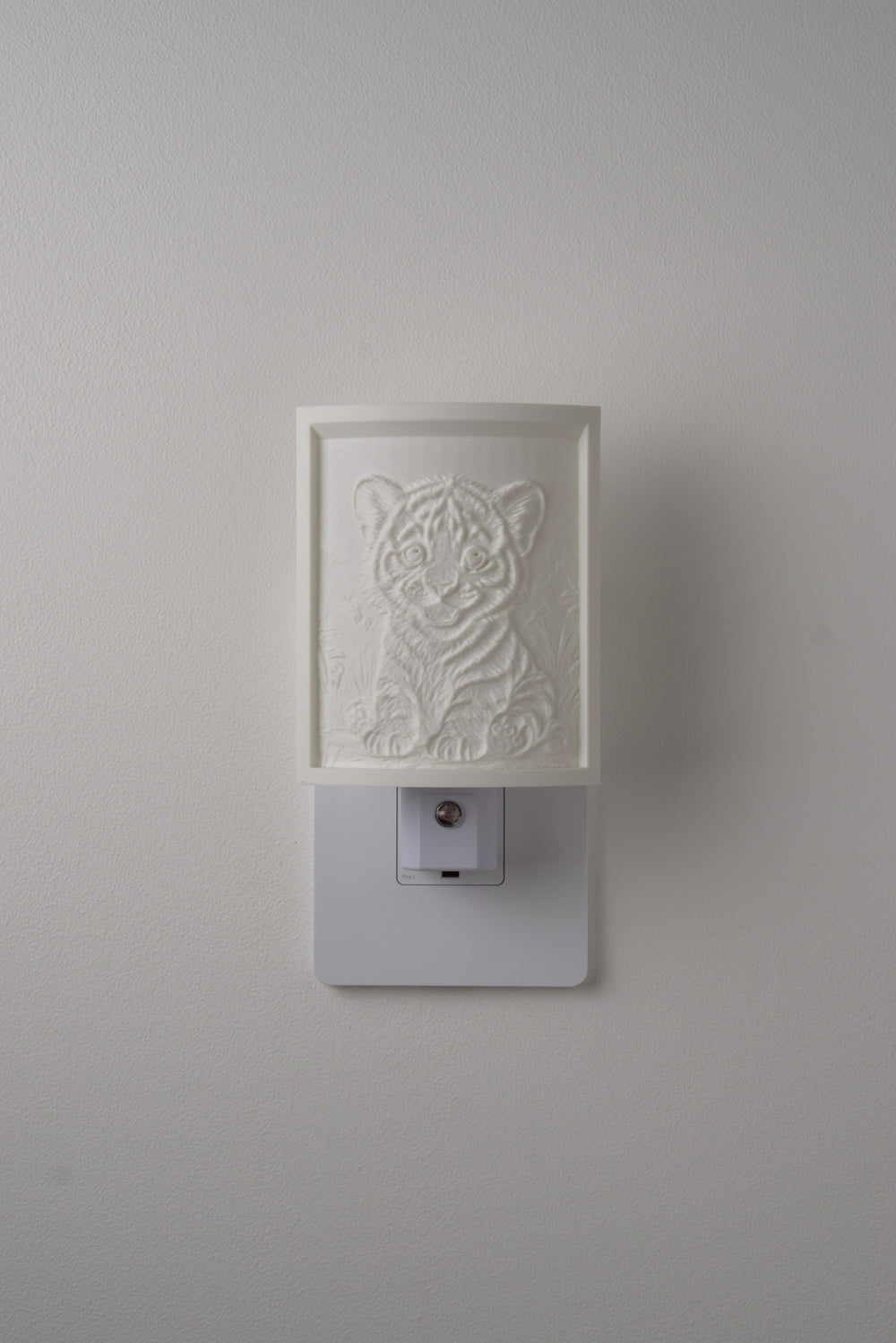 Tiger night light switched off — a soft ivory panel by day