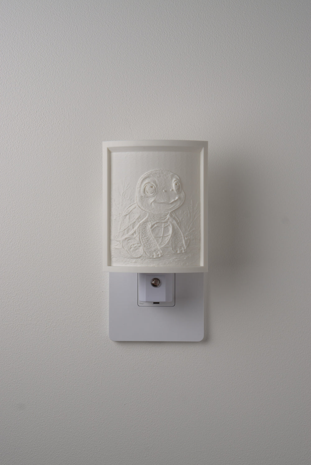 Tortoise night light switched off — a soft ivory panel by day
