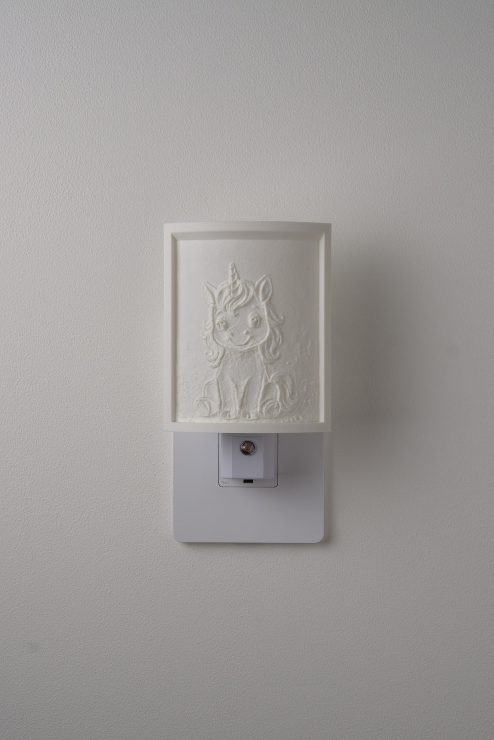 Unicorn night light switched off — a soft ivory panel by day
